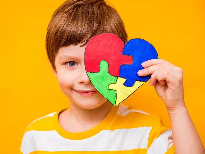 Niño sosteniendo un corazón de piezas de colores